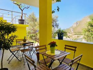 a patio with tables and chairs and a yellow wall at Lemon House Borsh in Himare