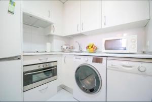 a white kitchen with a washing machine and a microwave at campezo in Madrid