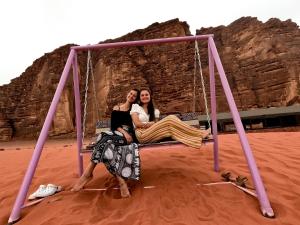 瓦迪拉姆Stargazing Camp & Tours的两个女人坐在沙漠的秋千上