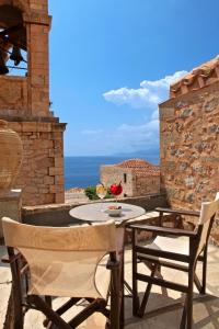 una mesa y sillas en un patio con vistas al océano en Byzantino Boutique Hotel en Monemvasía