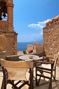 uma mesa e cadeiras num pátio com vista para o oceano em Byzantino Boutique Hotel em Monemvasia