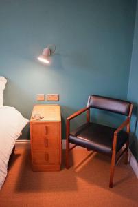 a bedroom with a chair and a bed and a nightstand at The Alma Taverns Boutique Suites - Room 5 - Hopewell in Bristol