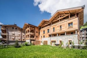 un gran edificio de madera con un campo de césped delante en Apartment Pamir Les Gets - by EMERALD STAY, en Les Gets