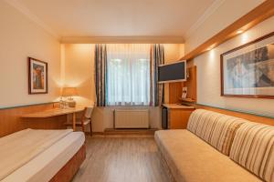 a hotel room with a bed and a desk at Parkhotel Crombach in Rosenheim