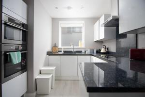 una cucina con armadietti bianchi e ripiani neri di Deluxe Apartment near Cabot Circus w Parking sleeps 5 a Bristol