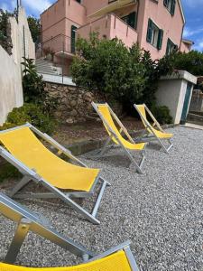 three yellow chairs sitting on the ground in front of a building at Appartamento Giardino e Parcheggio in Borgio Verezzi