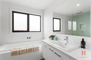une salle de bain blanche avec une baignoire et un lavabo dans l'établissement Hot Tub 4Bdr 2Ba Family Home, à Cape Woolamai 23 autres photos