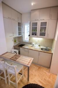 a kitchen with white cabinets and a table and chairs at Apartment Dositej 3 in Belgrade