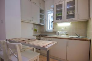 a kitchen with white cabinets and a sink and a table at Apartment Dositej 3 in Belgrade
