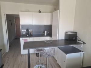 a kitchen with white cabinets and a black counter top at Plage à pieds in Théoule-sur-Mer
