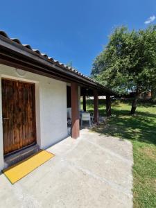a house with a large wooden door and a patio at Apartmani & Auto kamp GAJ in Gacko
