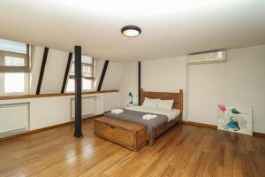 Un dormitorio con una cama en una habitación con suelo de madera. en Vintage Mezzanine Apt in City Center - By Wehost, en Tiflis 38 fotos más