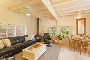 a living room with a black leather couch and a table at Kilara Cottage 3-Bed 2-Bath in Cowes