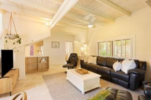 a living room with a black leather couch and a table at Kilara Cottage 3-Bed 2-Bath in Cowes