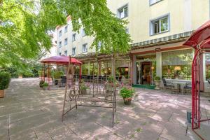 a patio with tables and umbrellas in front of a building at Parkhotel Crombach am Salingarten in Rosenheim