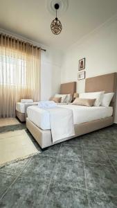 two beds in a white bedroom with a large bed at CALAYS Tu hogar junto al mar - ideal CAN2025 in Tangier