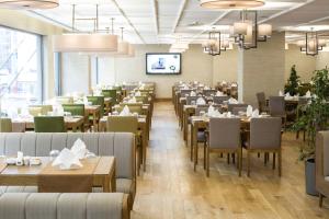 a dining room with tables and chairs and a tv at Ramada Hotel & Suites by Wyndham Adana in Adana