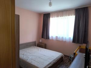 a small bedroom with a bed and a window at Апартамент за гости Александър in Chepelare