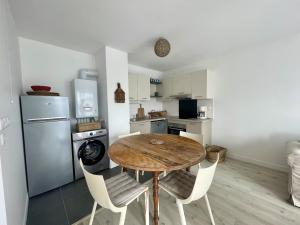 une cuisine avec une table, des chaises et un réfrigérateur dans l'établissement Le Croix de Vie, à Saint-Gilles-Croix-de-Vie