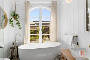 a white bathroom with a tub and a window at Charming 4 BR Cottage Retreat in Newhaven +23 photos