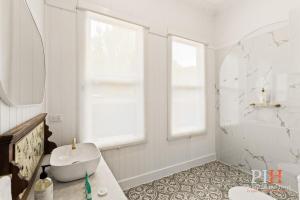 a white bathroom with a sink and a mirror at Charming 4 BR Cottage Retreat in Newhaven