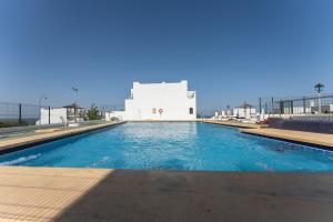 a swimming pool with a white building in the background at Casa la Buganvilla-Mojácar Playa in Mojácar