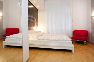 a bedroom with two beds and two red chairs at Diana Apartment On Váci Utca in Budapest