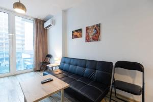Una sala de estar con un sofá de cuero negro y una mesa. en Cozy Studio Apartment For 3 with a pool, en Batumi 18 fotos más