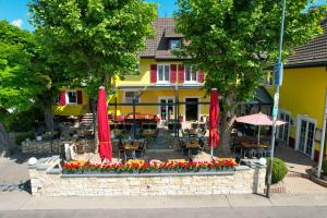 ein Restaurant mit roten Sonnenschirmen und Blumen vor einem Gebäude in der Unterkunft Tuniberg Restaurant Hotel in Freiburg im Breisgau