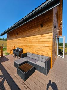 a patio with a couch and chairs on a wooden deck at Rogate Chatki in Lutowiska