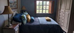 ein Schlafzimmer mit einem Bett mit blauen Laken und einem Fenster in der Unterkunft Ouma Bettie Guesthouse in Piketberg