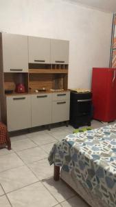 una cucina con mobili bianchi e un letto in una stanza di Ytamãní l apartamentos a Santa Cruz Cabrália