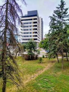 a park with trees and a tall building at Lovely apartment near NS Fair in Novi Sad