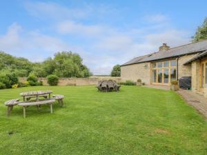 a yard with two picnic tables and a building at Lower Farm Barn in Oxford