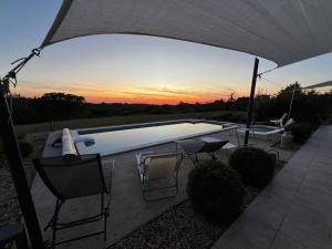 una piscina con sillas y sombrilla en Villa coucher de soleil, en Pontours