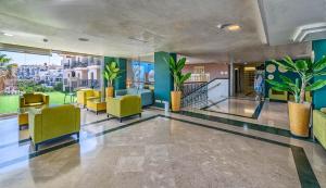 eine Lobby mit gelben Stühlen und Pflanzen in einem Gebäude in der Unterkunft Benalmadena Palace Spa in Benalmádena + 37 Fotos