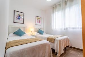 two beds in a room with white walls and blue pillows at MARITIM Family Muntanya Ambar in Salou