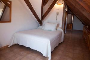 a white bed in a room with wooden ceilings at Hostal Mar de Frente in Los Caños de Meca