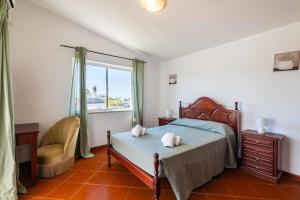 a bedroom with a bed and a chair and a window at Villa Eulália in Guia