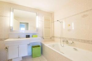 モントルーにあるAlpine Stunning Apartment in Montreux by GuestLeeの浴槽、洗面台、鏡のあるバスルーム