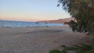 a beach with umbrellas and people on the water at Sotiris Mandarin house in Diakopto