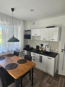 a kitchen with white cabinets and a wooden table at Vila DRAGONFLY in Šventoji