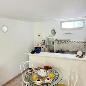 a kitchen with a glass table with food on it at Studio agréable en forêt in Saint-Jouan-des-Guérets