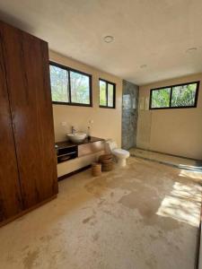 a bathroom with a toilet and a sink and windows at Villa Natural en Chemuyil in Balcheil
