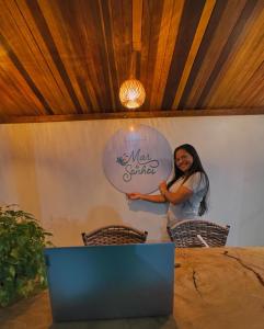 Eine Frau steht vor einem Tisch mit einem Schild. in der Unterkunft Pousada Mar de Sonhos in Maragogi