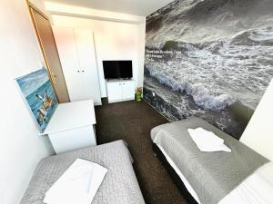 a bedroom with two beds and a tv and a painting at Sztorm Rowy in Rowy