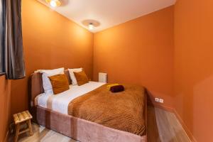 a bedroom with a bed with orange walls at MARAIS POMPIDOU 3e, jacuzzi, 2 chambres, 4 à 6P in Paris