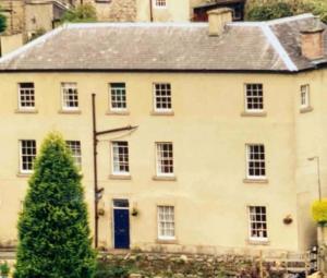 a white house with a blue door and a tree at Jubilee View, Studio Apartment in Matlock Bath in Matlock Bank