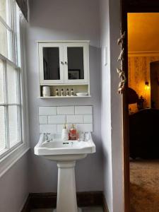a white bathroom with a sink and a window at Jubilee View, Studio Apartment in Matlock Bath in Matlock Bank +10 photos