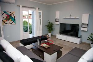a living room with a couch and a tv at Aroura Maisonette Spetses 4BR in Spetses